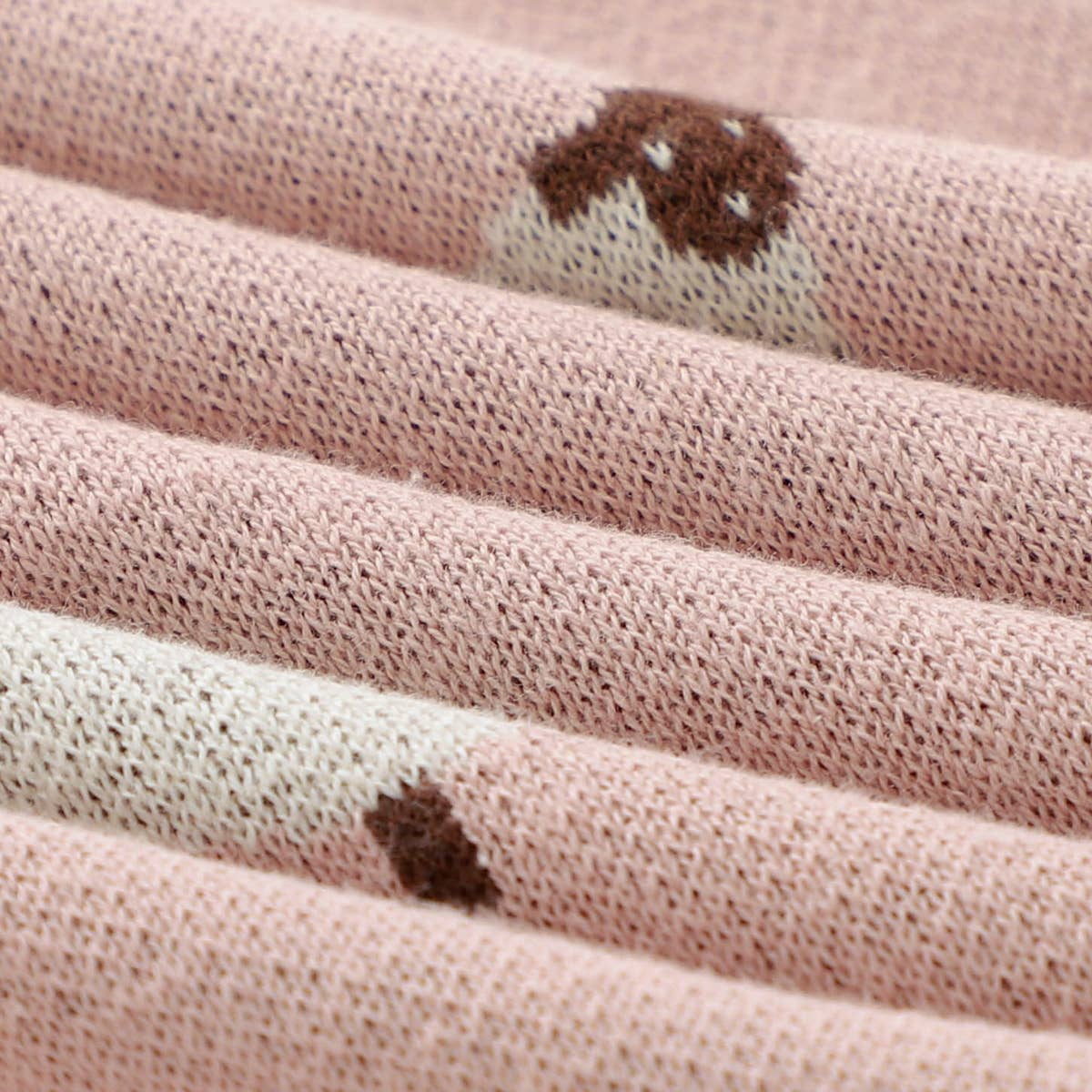 Close-up of pink fabric with brown paw prints, possibly from a children's garment.