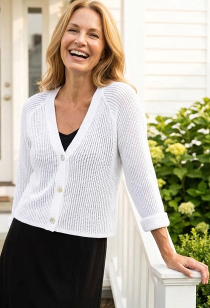Habitat Sunburst Knit Cardigan in white, front view styled with black skirt, showing V-neck, pearl buttons, and open sunburst knit texture