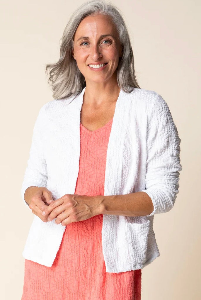 Front view outdoors — "Habitat Women's Sunburst Knit Cardigan in white worn open over a coral dress, front view, smiling model outdoors"
Front three-quarter view — "Habitat Women's Sunburst Knit Cardigan in white, front three-quarter view on model with coral dress, neutral background"
Back view — "Habitat Women's Sunburst Knit Cardigan in white, back view showing textured knit detail and peplum hem"
Close-up front — "Habitat Women's Sunburst Knit Cardigan in white, close-up front view showing open front and
