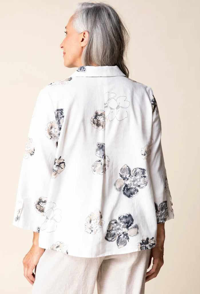 Front view (brunette model) — "Habitat Women's Watercolor Floral Swing Shirt in white with navy and taupe floral print, front view, smiling brunette model styled with linen trousers"
Back view (brunette model) — "Habitat Women's Watercolor Floral Swing Shirt in white with navy and taupe floral print, back view showing relaxed swing silhouette and 3/4 sleeves"
Close-up front — "Habitat Women's Watercolor Floral Swing Shirt in white with navy and taupe floral print, cropped front close-up showing button plack