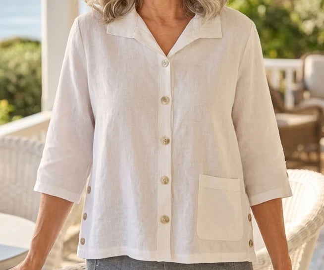 Front view (studio) — "Habitat Women's Favorite Camp Shirt in white linen, front view on smiling curly-haired model, V-neck collar, button front, patch pocket, and 3/4 sleeves, styled with grey linen trousers"
Back view — "Habitat Women's Favorite Camp Shirt in white linen, back view showing center pleat detail and relaxed fit, styled with grey linen trousers"
Side close-up — "Habitat Women's Favorite Camp Shirt in white linen, close-up side view highlighting button placket, side snap buttons, and hem detai