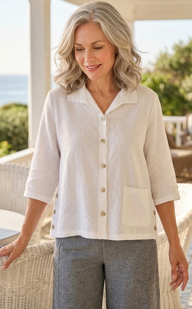 Front view (studio) — "Habitat Women's Favorite Camp Shirt in white linen, front view on smiling curly-haired model, V-neck collar, button front, patch pocket, and 3/4 sleeves, styled with grey linen trousers"
Back view — "Habitat Women's Favorite Camp Shirt in white linen, back view showing center pleat detail and relaxed fit, styled with grey linen trousers"
Side close-up — "Habitat Women's Favorite Camp Shirt in white linen, close-up side view highlighting button placket, side snap buttons, and hem detai