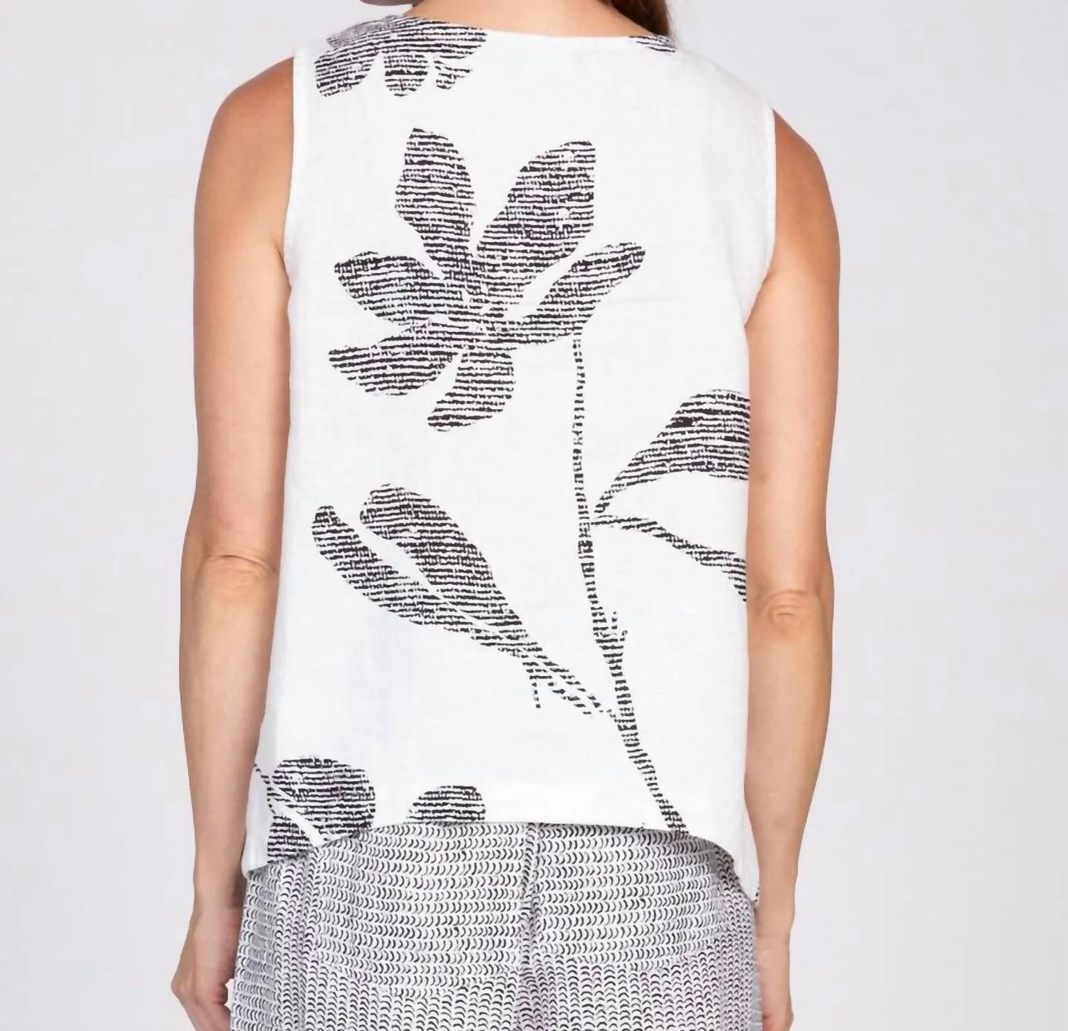 IMG_0133 — Women's white sleeveless tank top with black oversized floral bouquet print, front view, scoop neckline
IMG_0136 — Olivia women's white floral bouquet tank top, front torso view showing bold black botanical print
IMG_0135 — Women's white floral print tank top styled with black and white wide-leg pants and black platform sandals, full body front view
IMG_0134 — Women's white sleeveless tank top with large black leaf and floral print, back view
IMG_0137 — Close-up back view of women's white tank to
