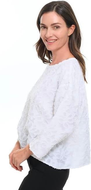 White floral appliqué topper, side view showing long sleeve and relaxed silhouette, styled with black leggings