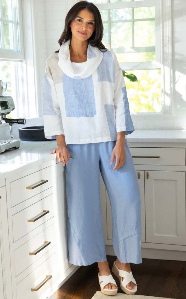 "Full-length view of woman in Olivia by Habitat blue and white colorblock linen cowl top paired with blue wide-leg linen pants and white platform sandals"
