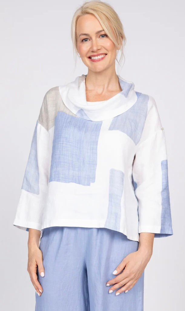 "Close-up front view of woman smiling in Olivia by Habitat blue and white hand-painted colorblock linen cowl neck top with 3/4 sleeves"