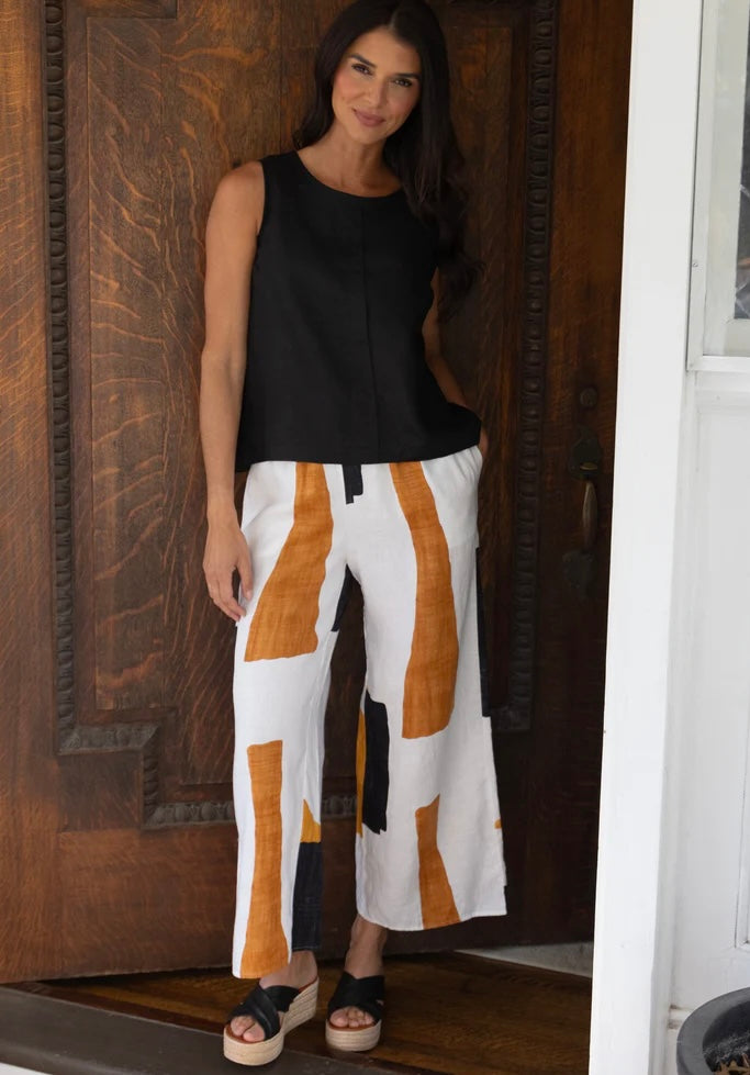 "Woman wearing Olivia Coastal Colorblock Breeze Pant in white abstract print with black sleeveless top and black wedge sandals, full-length front view"