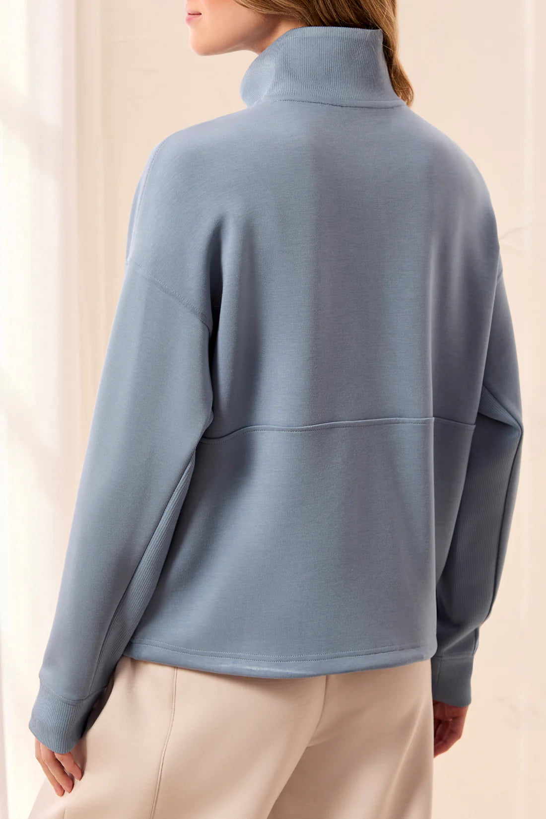 Person wearing a blue pullover with a neutral background