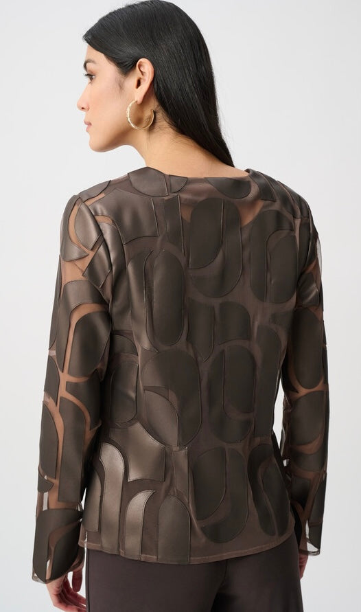 A woman shown from the back wearing a dark brown and black patterned long-sleeve top with a structured, sculptural design, set against a plain light gray background.