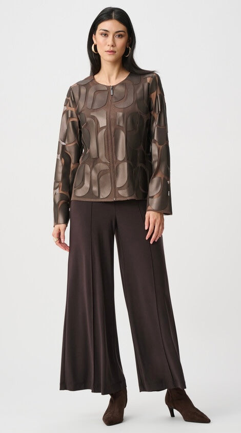A model wearing a brown and beige patterned long-sleeve top paired with dark brown wide-leg trousers and brown heeled boots, standing against a light gray studio background.