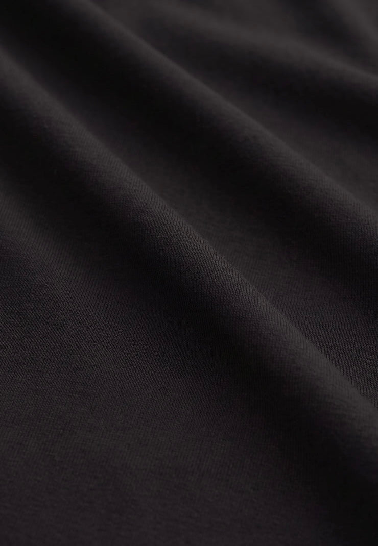 A close-up of dark charcoal gray or black textured fabric with soft folds and a fine woven surface.