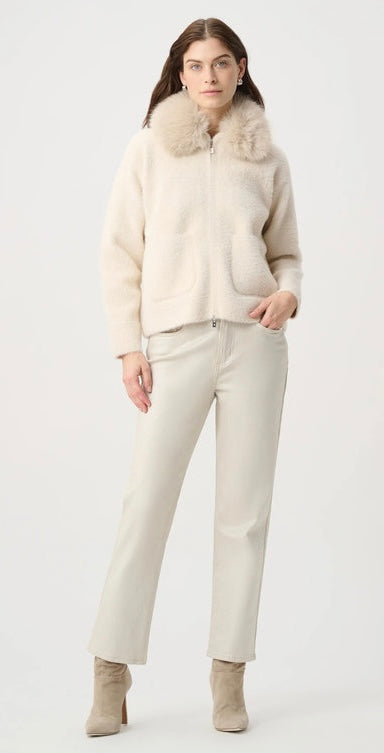 A model wearing a cream-colored faux fur jacket with a large collar, paired with matching cream trousers and beige ankle boots, against a plain white studio background.