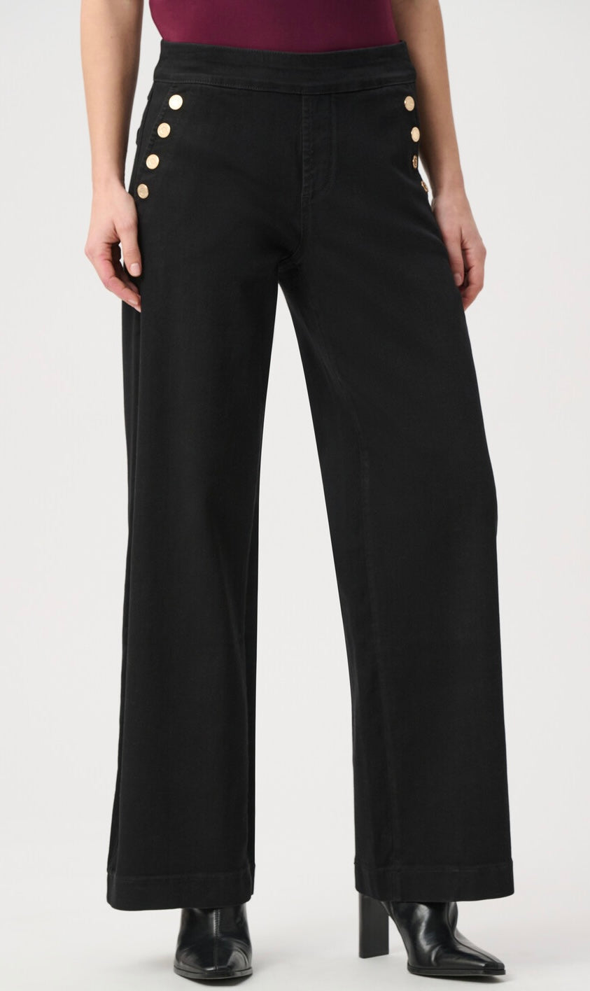 Black wide-leg pants with decorative gold buttons on the front of the hips, shown on a model wearing a burgundy top and black heeled boots against a light gray studio background.