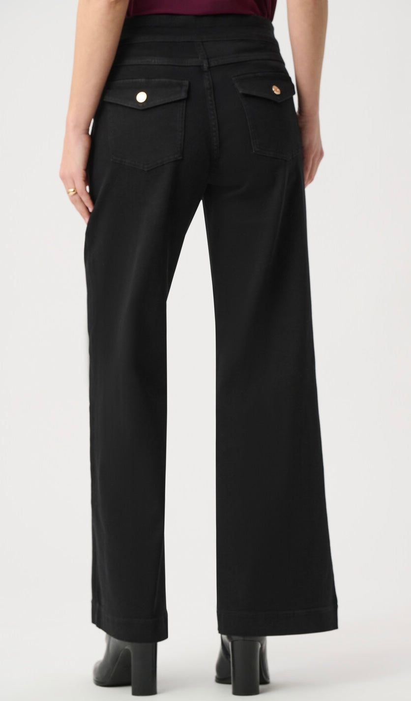 Black wide-leg jeans shown from the back on a model, featuring two buttoned flap pockets and a high waist, paired with black block-heel boots against a light gray studio background.
