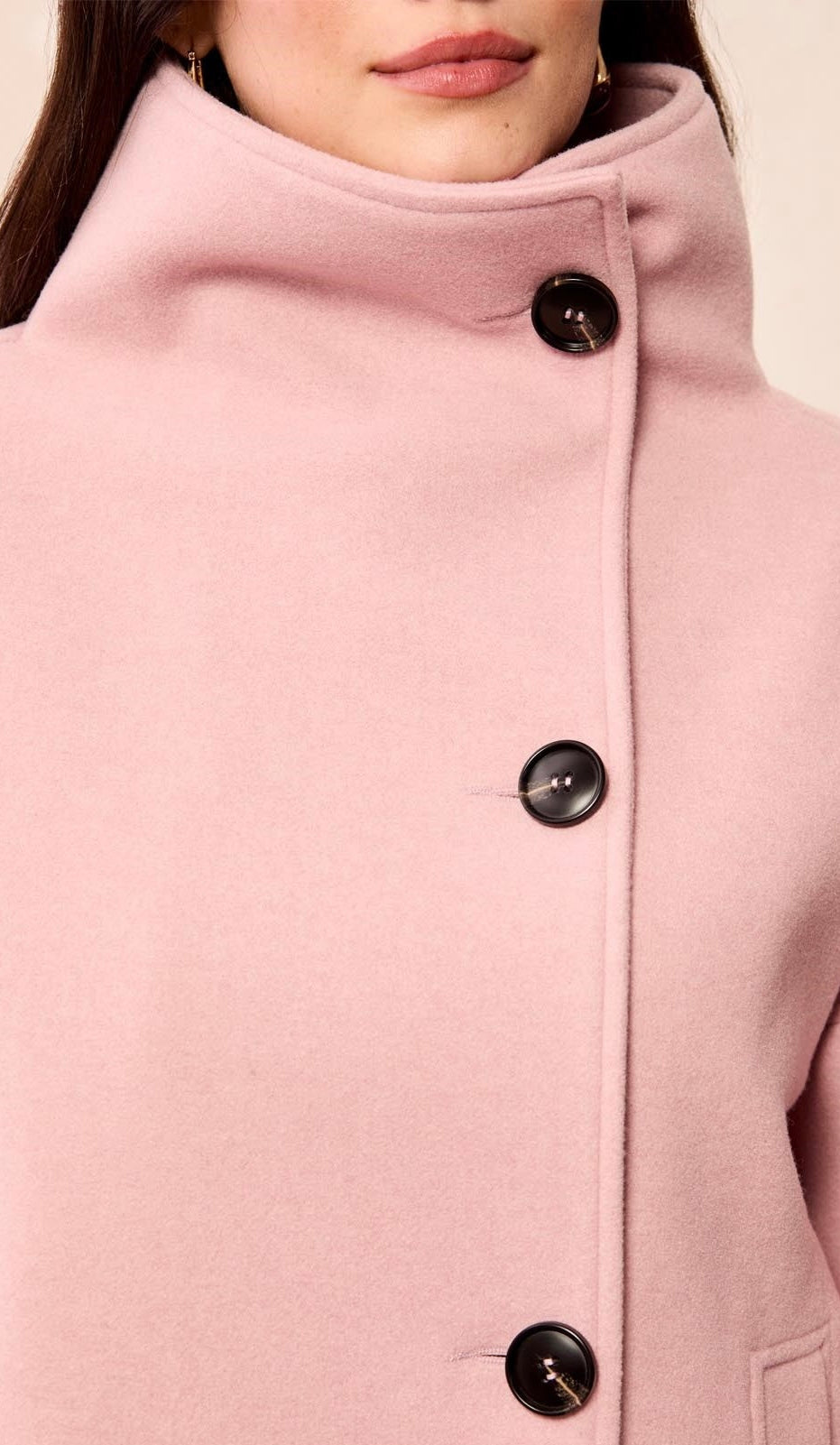 Close-up of a model wearing a dusty pink coat with a high stand collar and three black buttons. - OLIVIA'S
