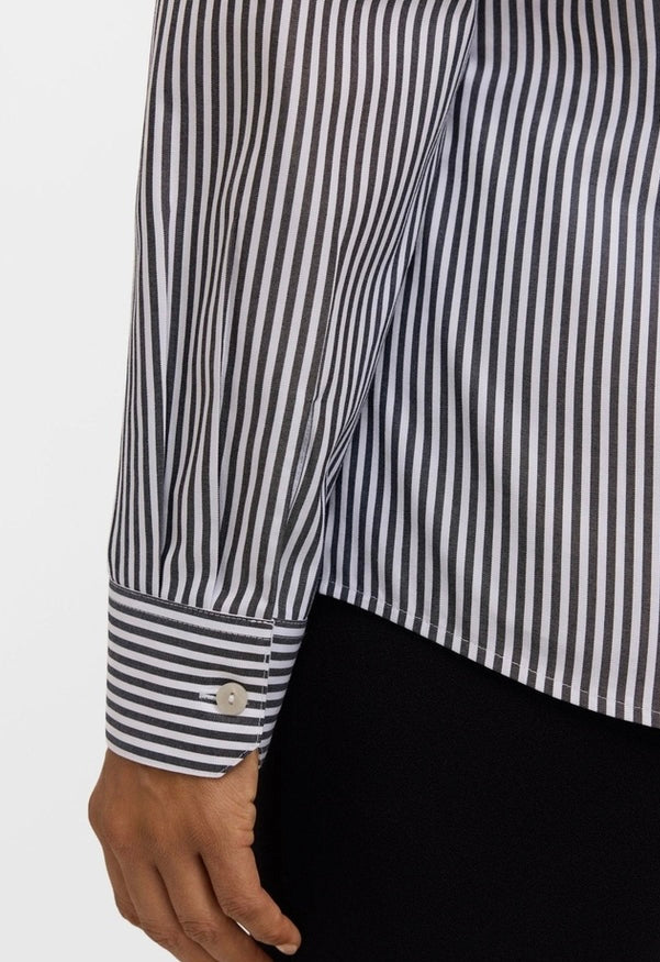 Close-up of a person wearing a black and white vertically striped button-down shirt with a single-button cuff, paired with black bottoms. - OLIVIA'S