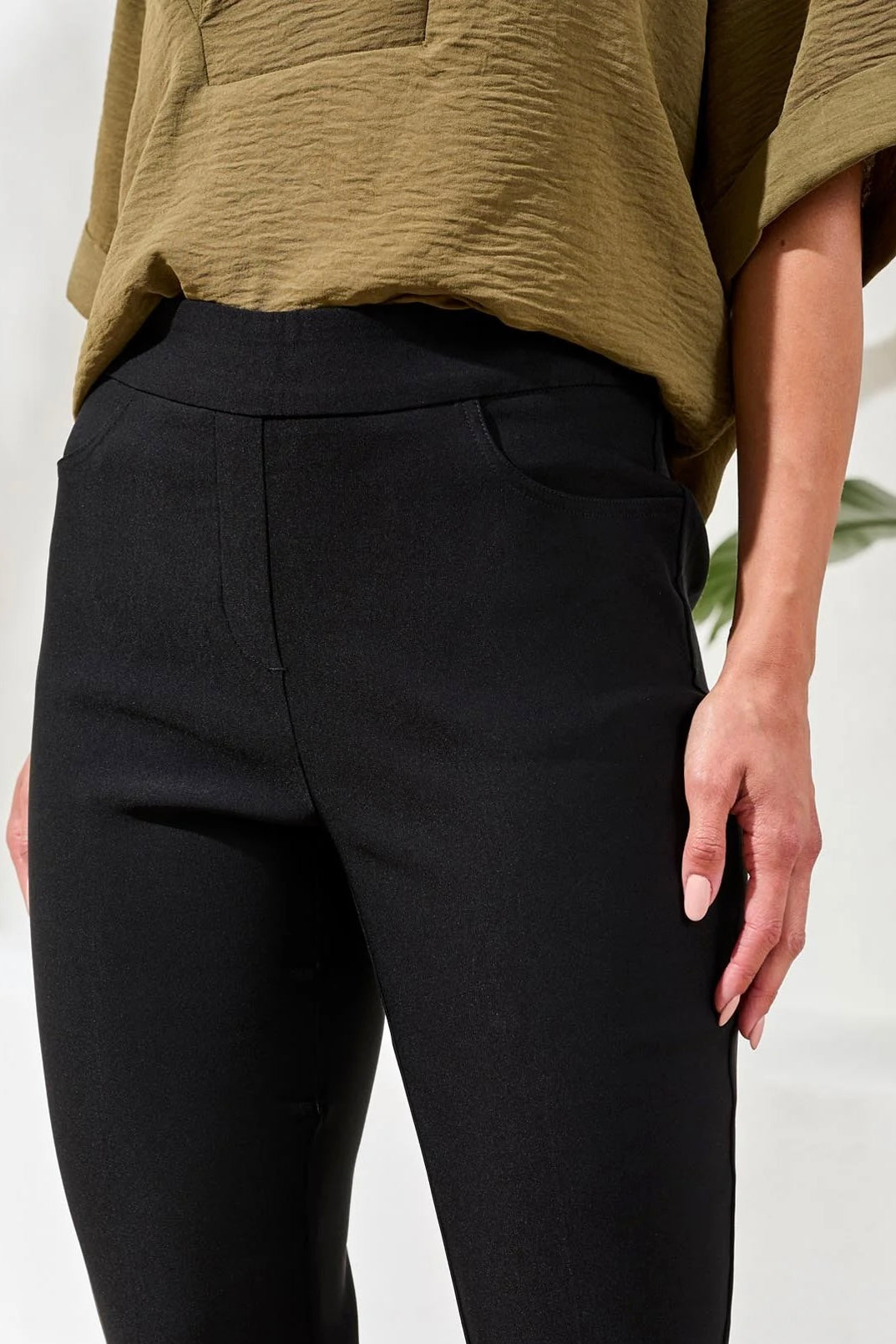Person wearing black pants and a green top on a white background