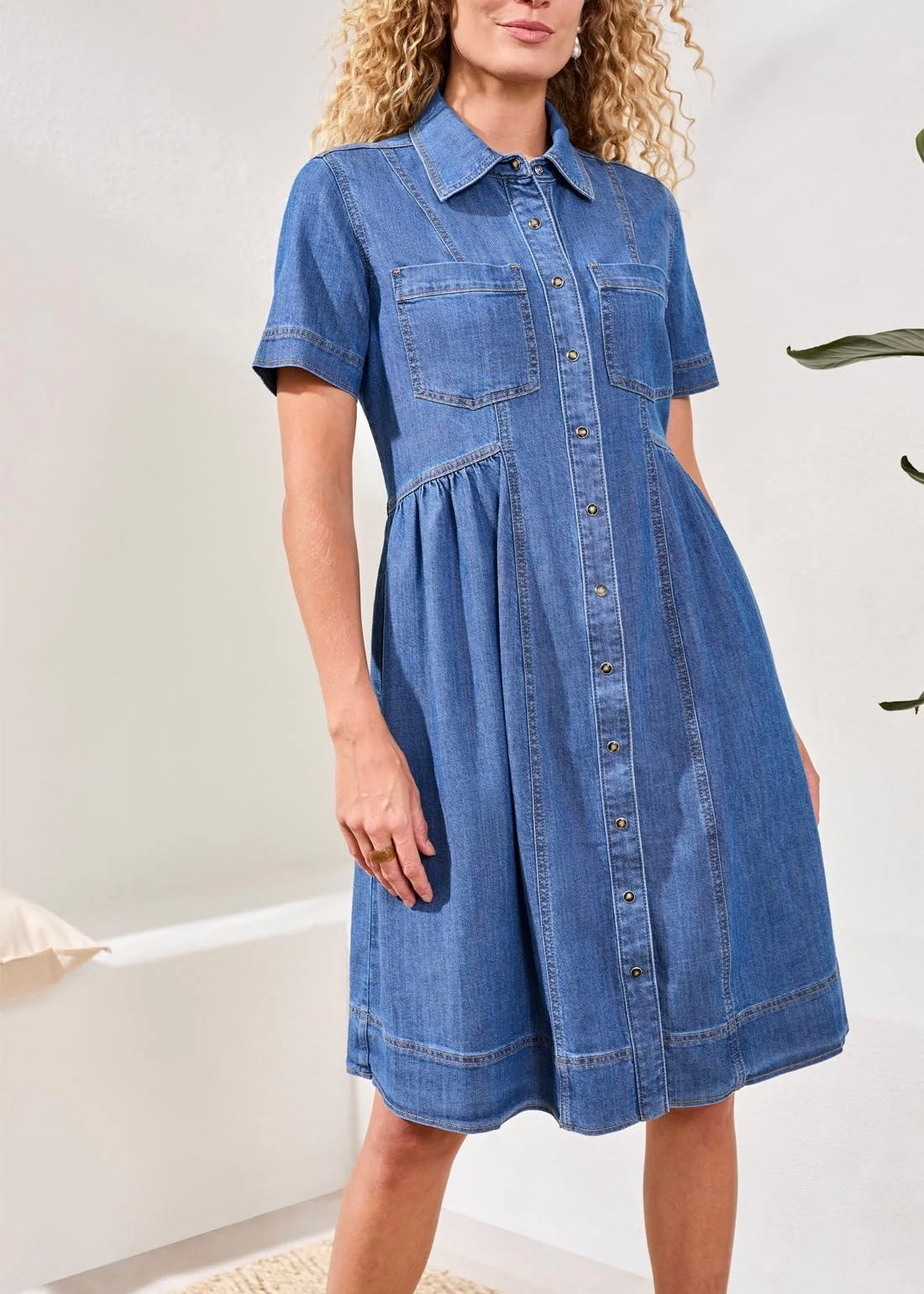 Woman wearing a blue denim dress against a white background