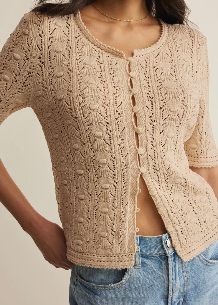 Beige knitted cardigan worn by a person with a neutral background