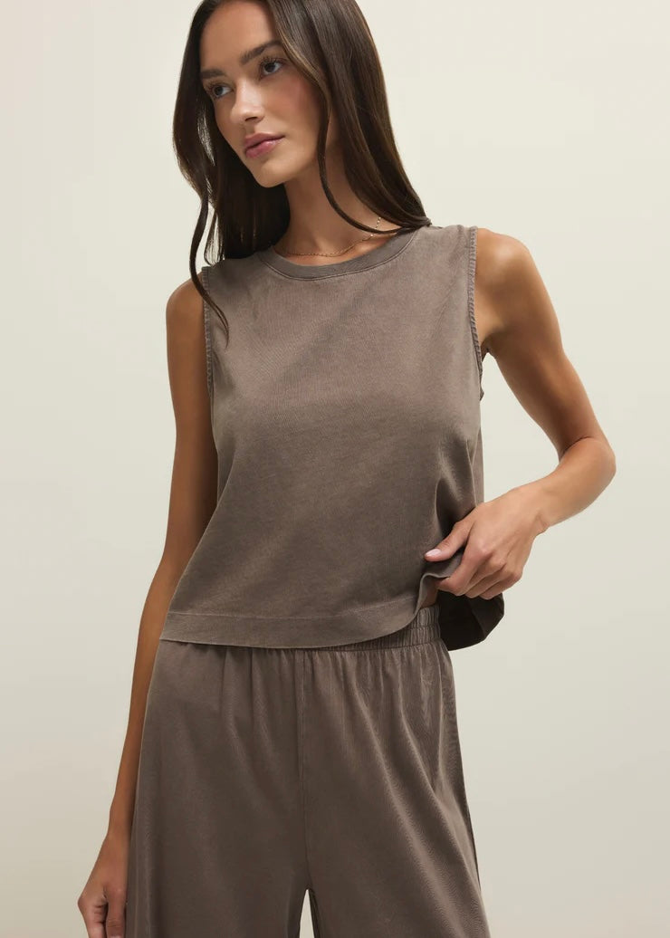 Woman wearing a brown sleeveless top and pants against a plain background