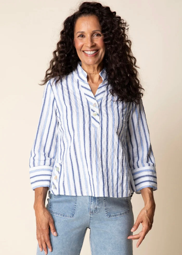 Woman wearing a blue and white striped shirt and jeans against a beige background