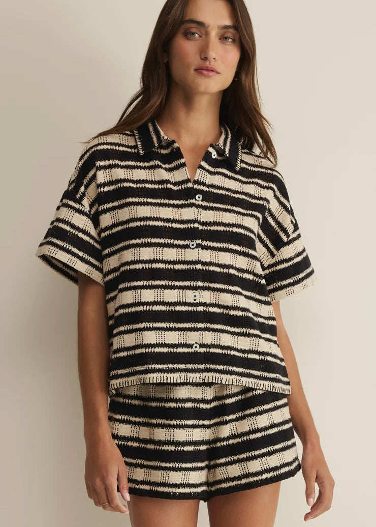 Woman wearing a black and white striped shirt and shorts on a plain background