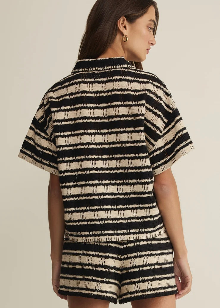 Person wearing a black and beige striped outfit on a plain background