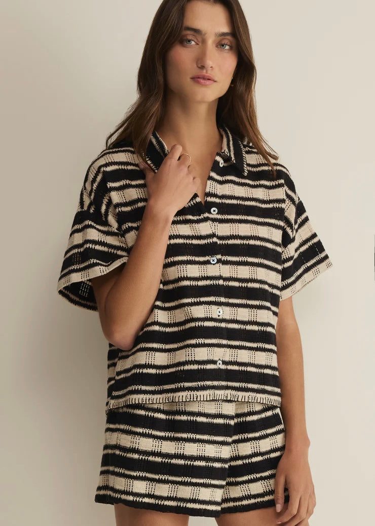 Woman wearing a black and white striped shirt against a plain background