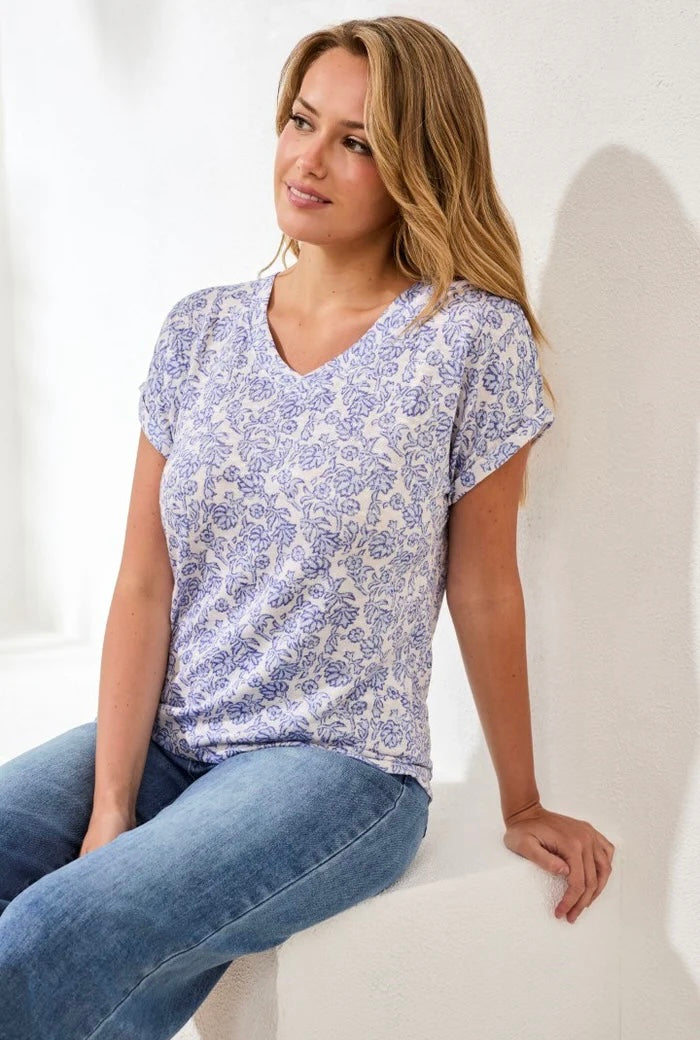 Woman wearing a blue and white patterned shirt sitting on a white chair.