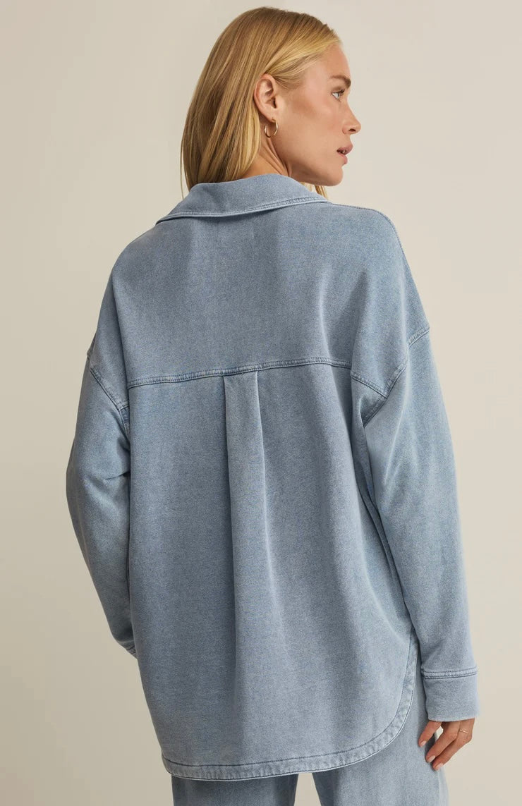 Person wearing a light blue denim jacket on a beige background