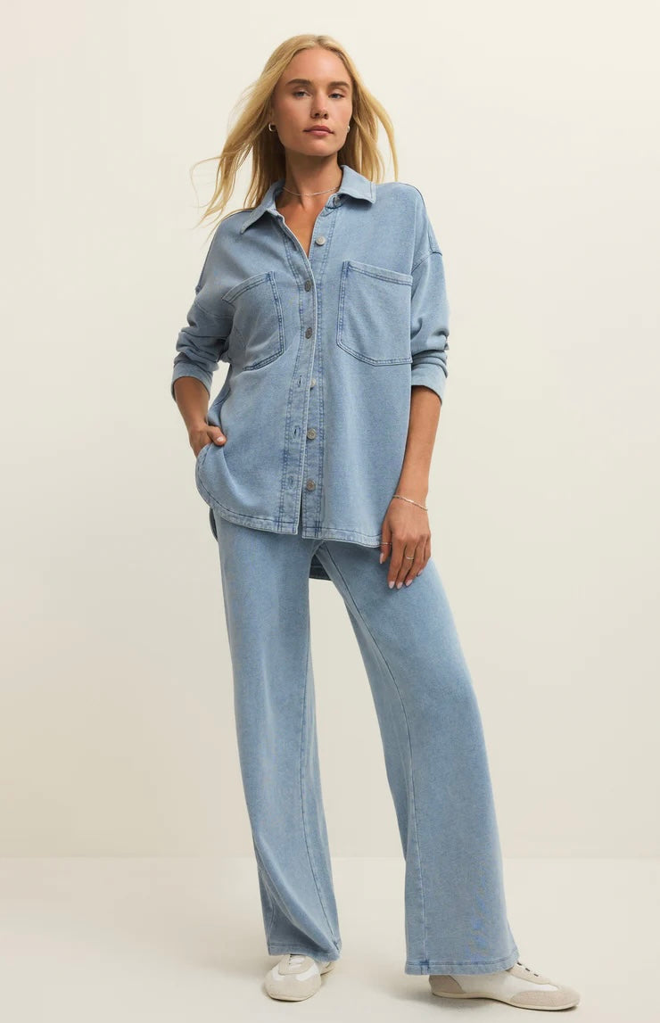 Woman wearing a light blue denim shirt and jeans on a plain background