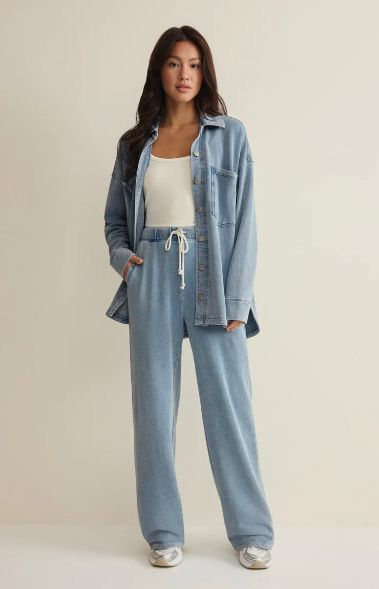 Woman wearing a denim jacket and pants on a plain background