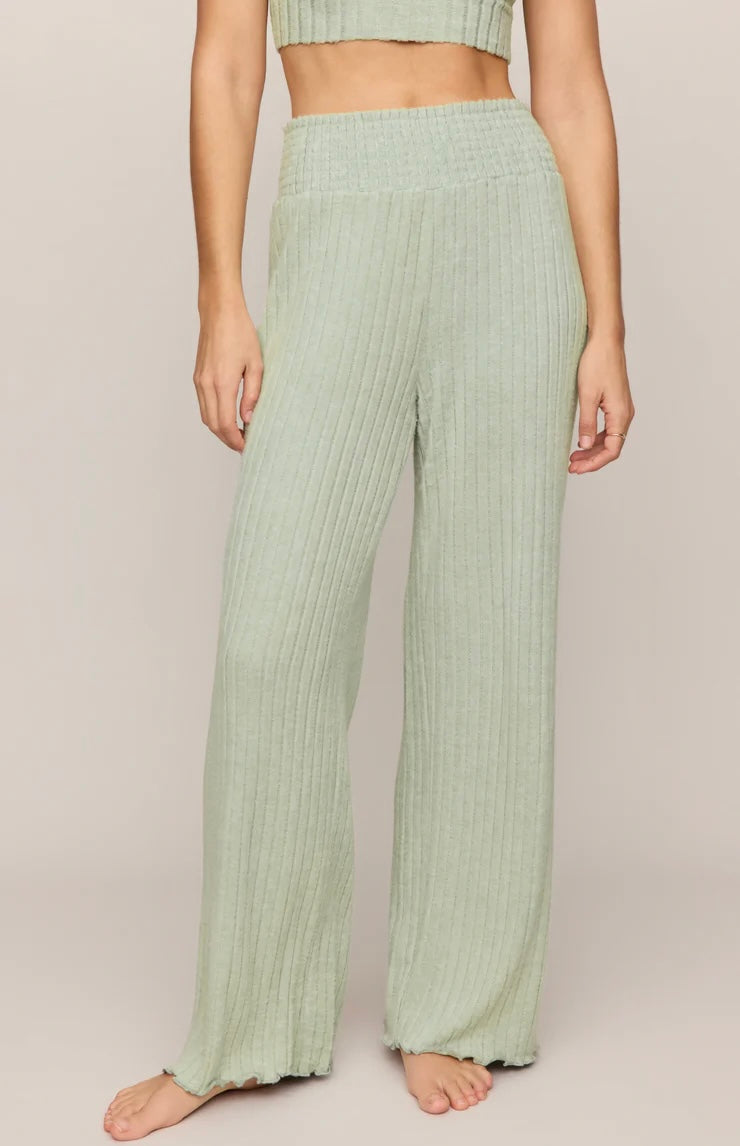 Person wearing light green ribbed pants on a plain background