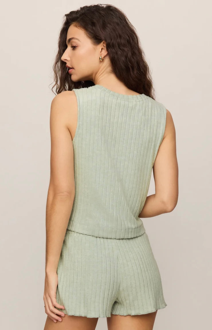 Woman wearing a light green ribbed romper against a plain background