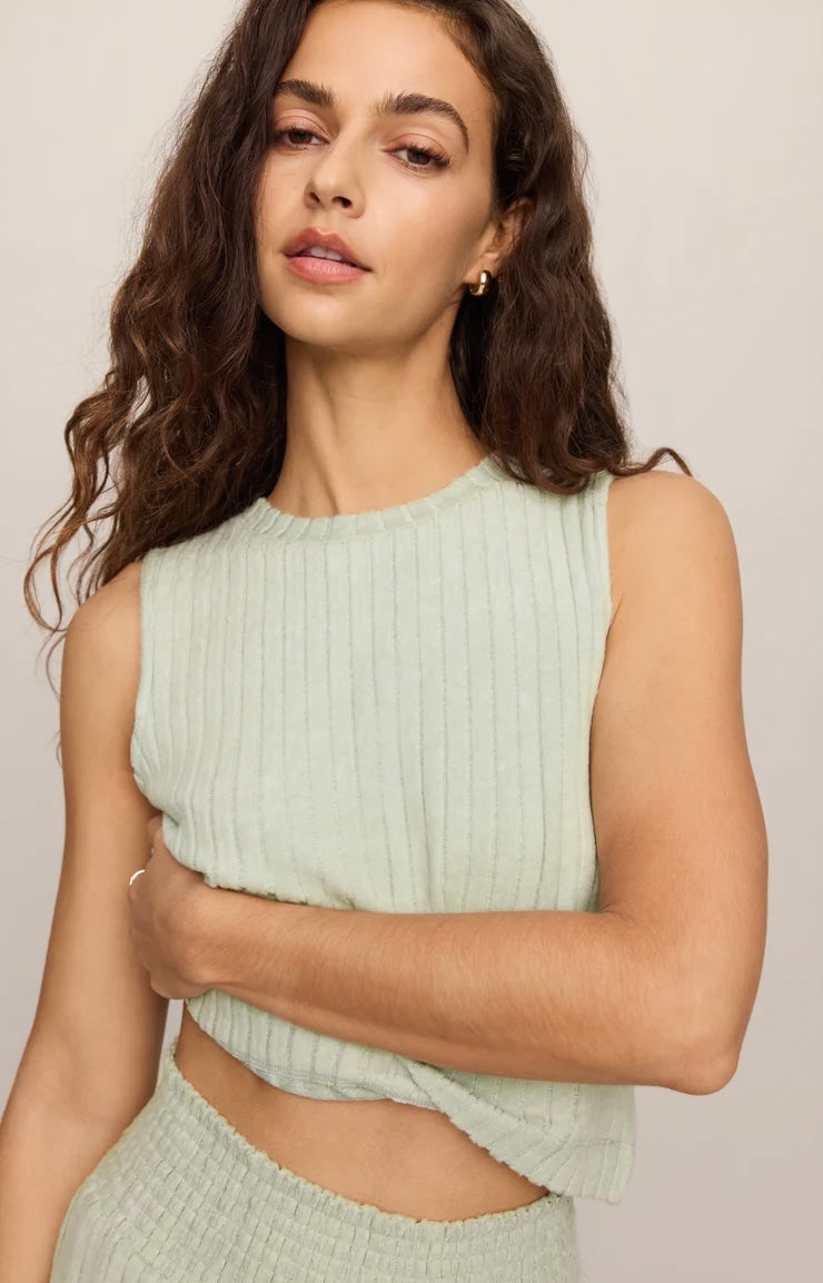 Woman wearing a light green sleeveless top with a plain background