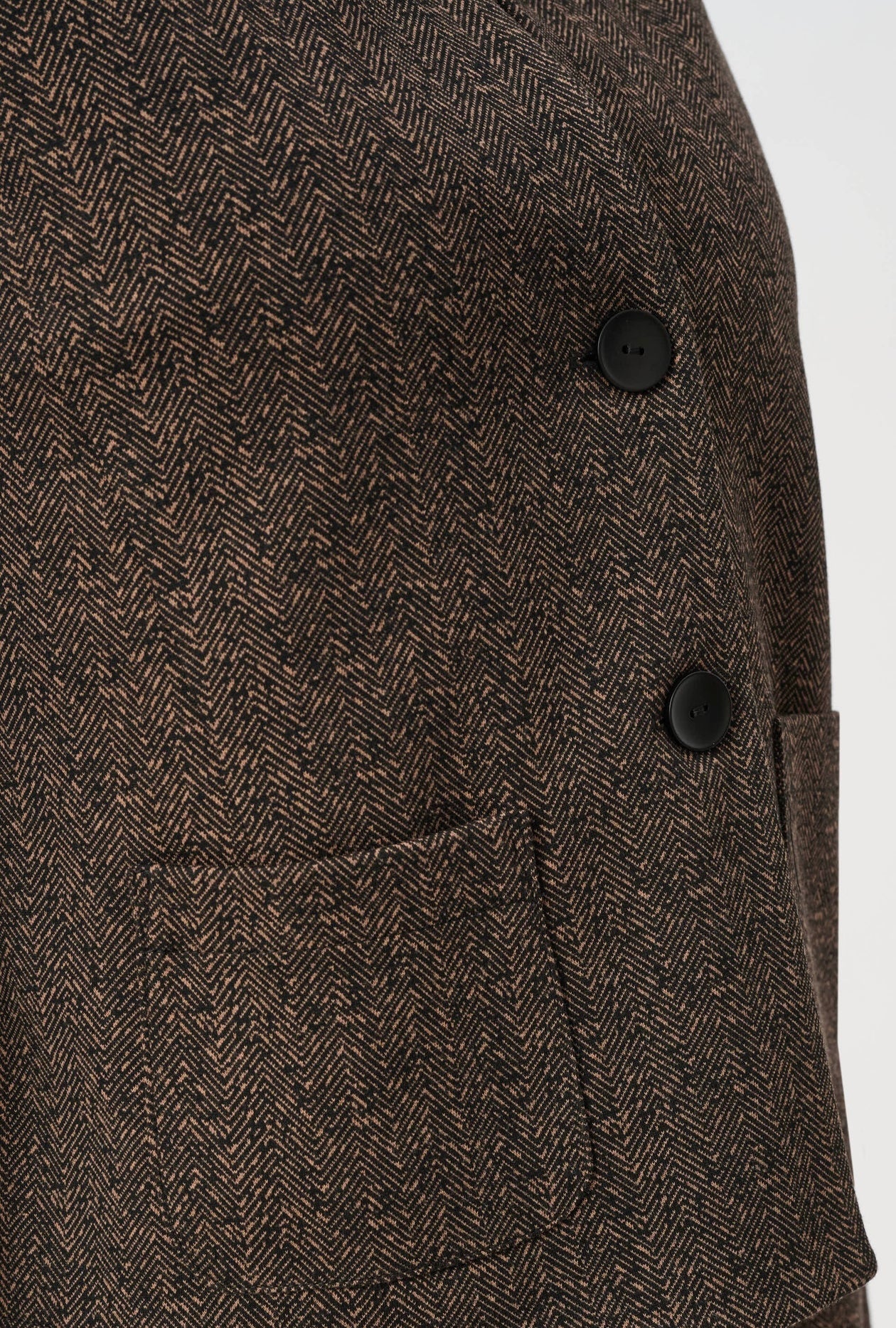 Brown herringbone patterned fabric with black buttons on a white background
