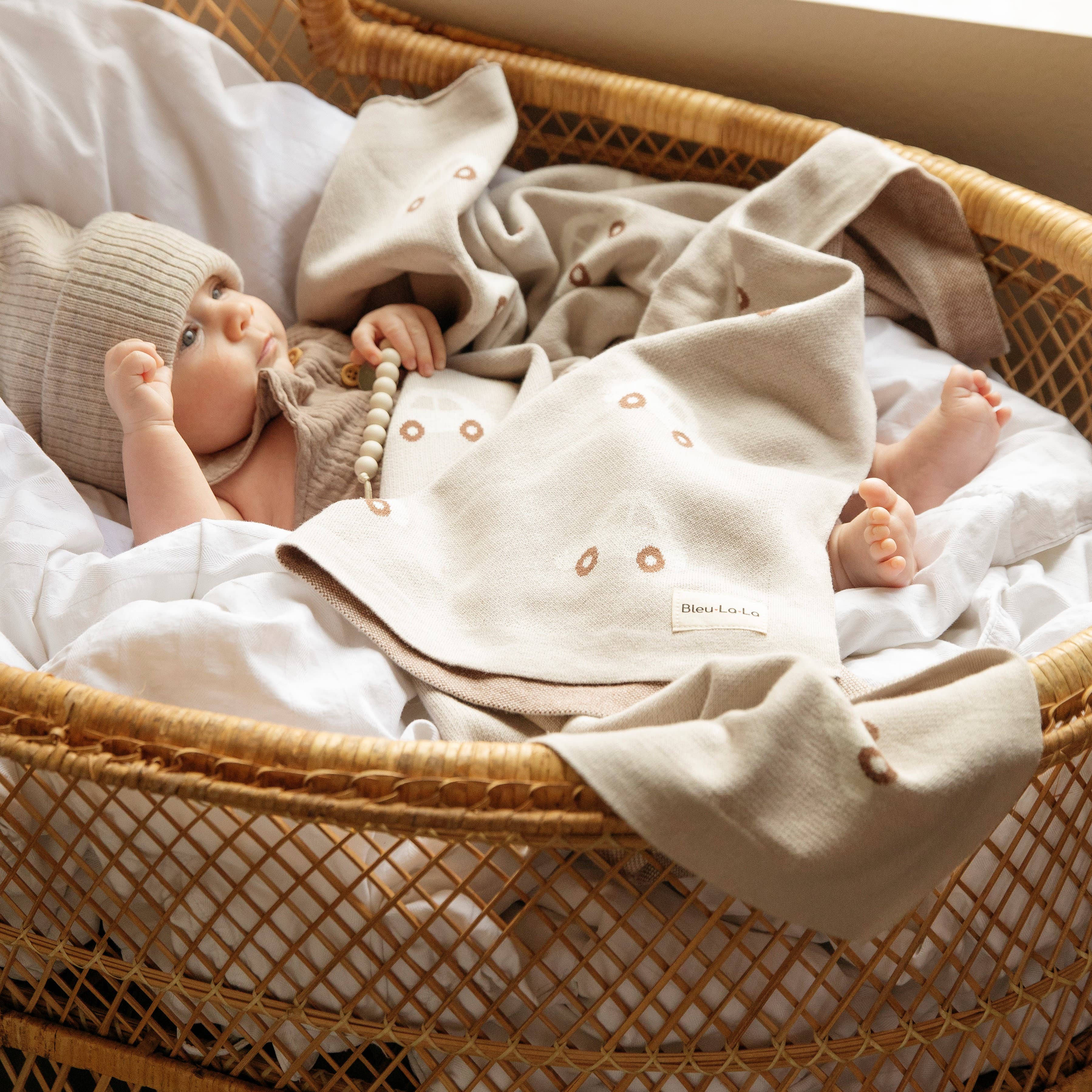 Baby doll in a wicker basket with a blanket and toy