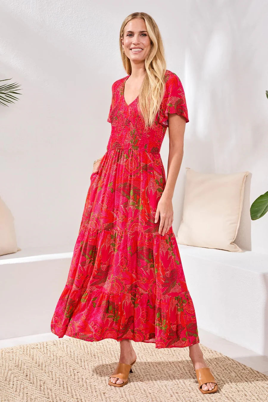 Woman wearing a red floral dress in a minimal indoor setting