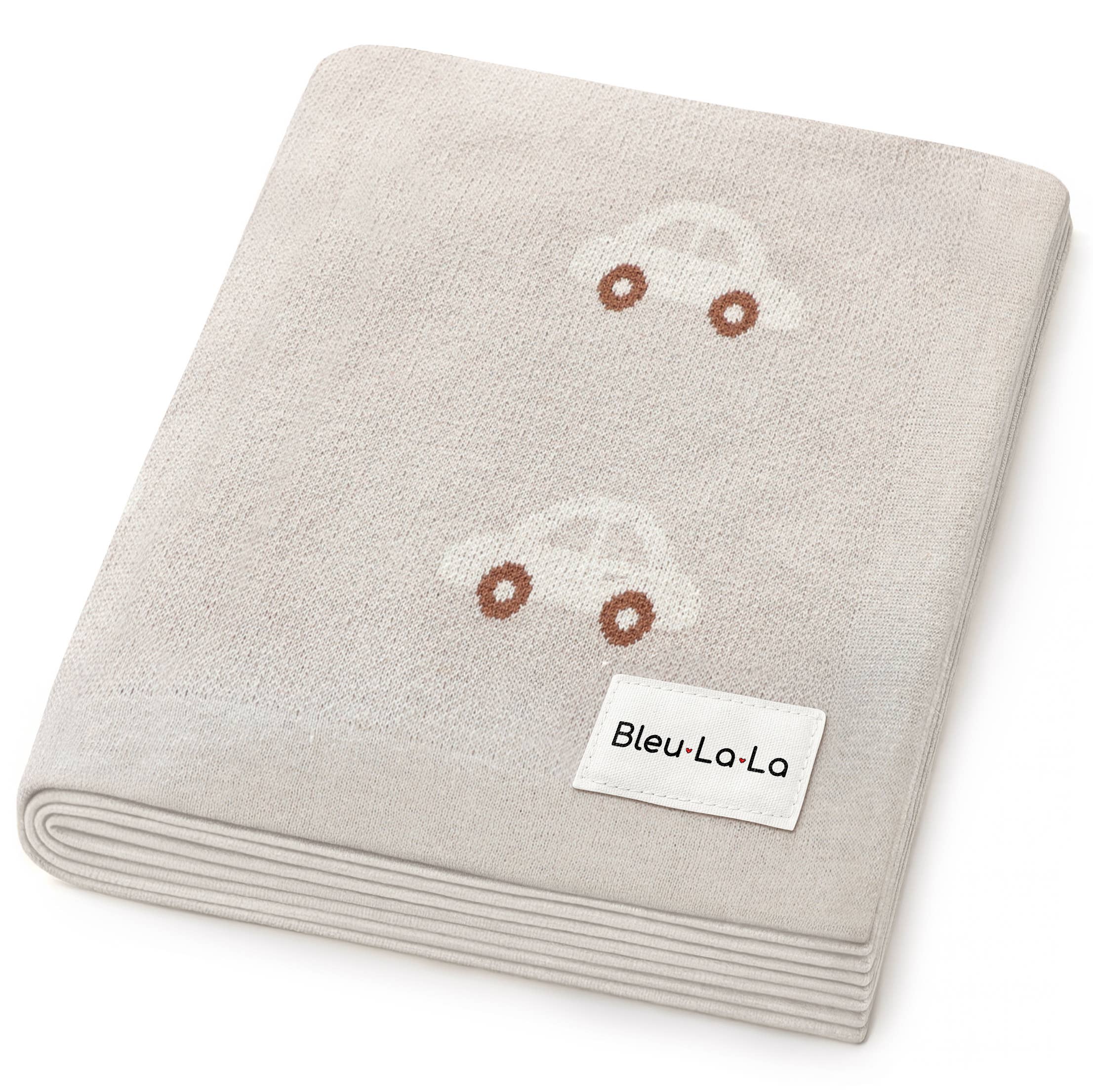 Folded beige blanket with embroidered faces and 'Bleu-La-La' label on a white background