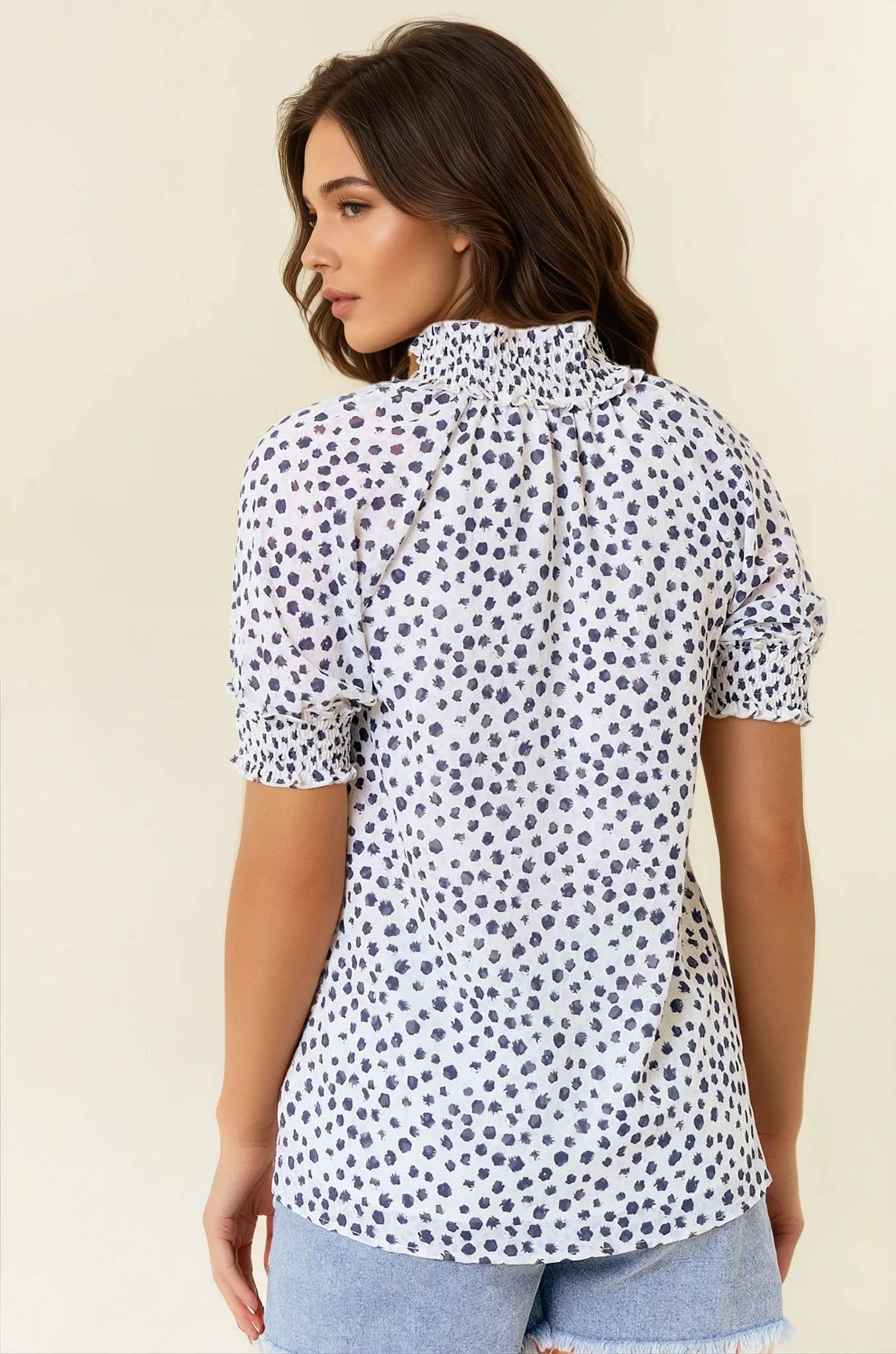 Woman wearing a white blouse with black polka dots on a beige background