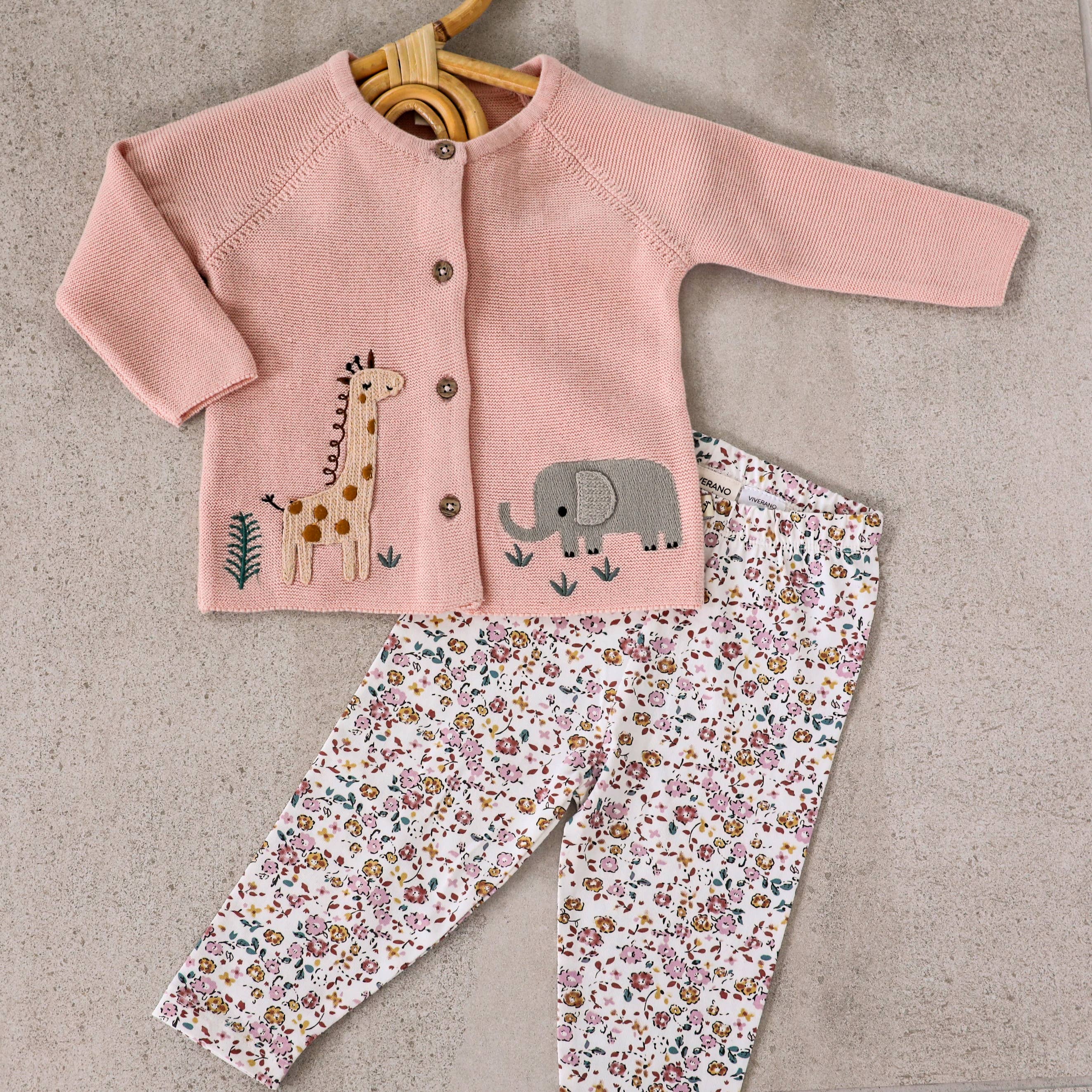 Pink cardigan with animal prints and floral pants on a beige background