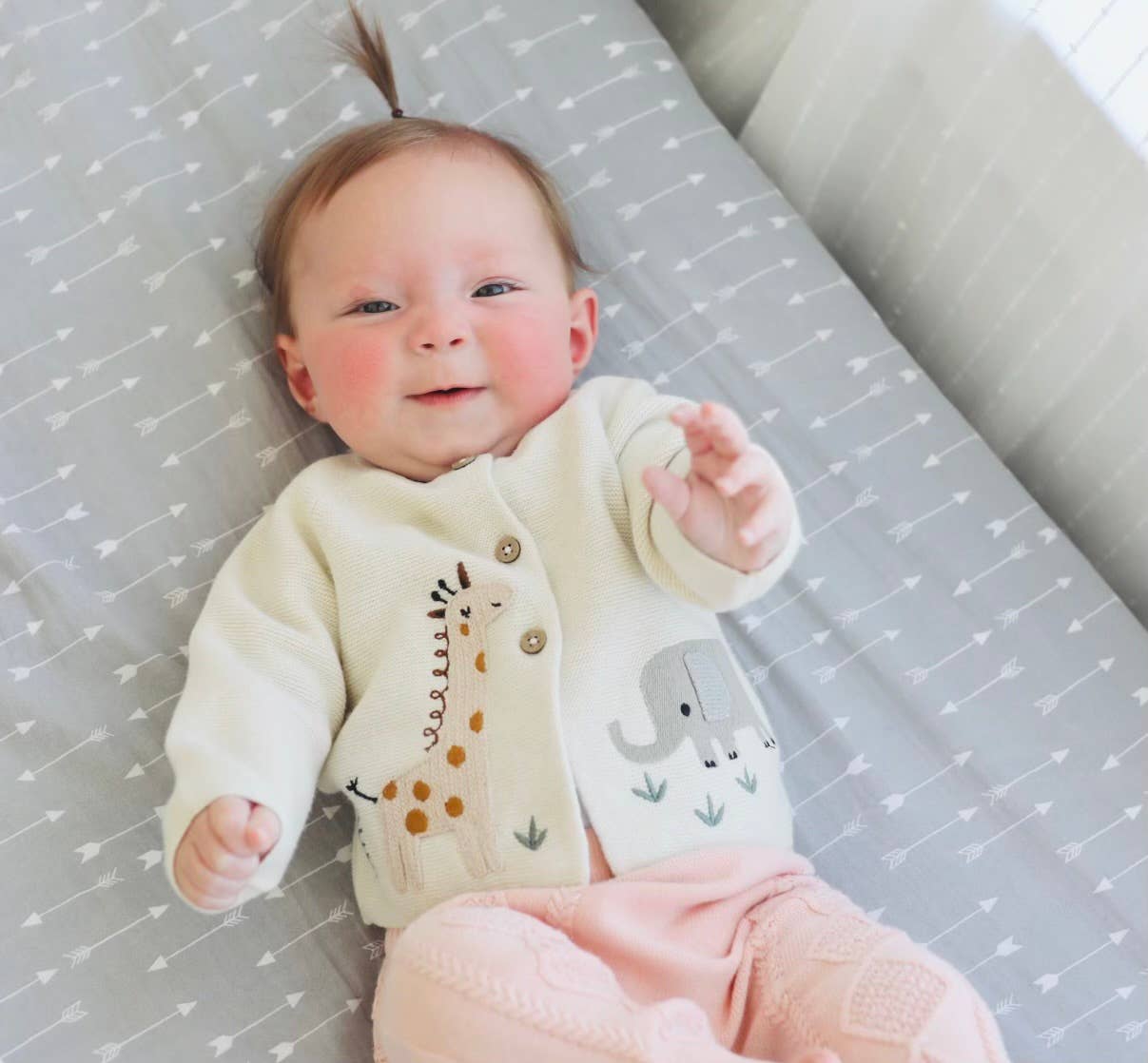 Baby lying on a crib with a patterned mattress cover