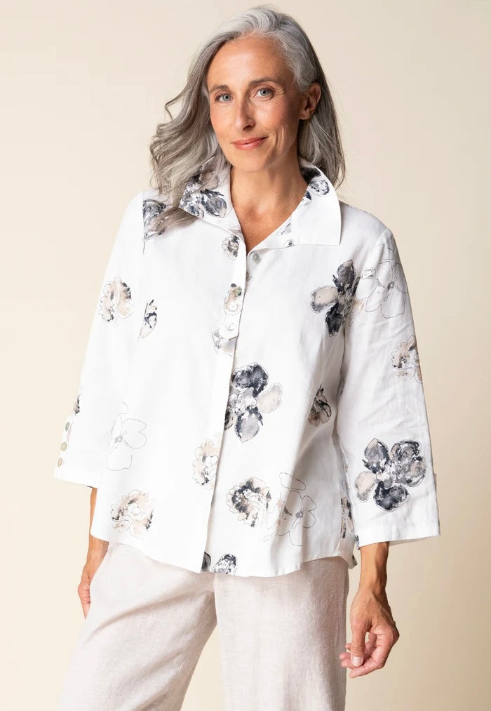 Front view (brunette model) — "Habitat Women's Watercolor Floral Swing Shirt in white with navy and taupe floral print, front view, smiling brunette model styled with linen trousers"
Back view (brunette model) — "Habitat Women's Watercolor Floral Swing Shirt in white with navy and taupe floral print, back view showing relaxed swing silhouette and 3/4 sleeves"
Close-up front — "Habitat Women's Watercolor Floral Swing Shirt in white with navy and taupe floral print, cropped front close-up showing button plack