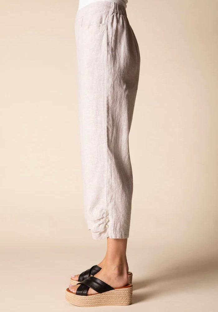 Front view (studio) — "Habitat Women's Linen Solid Pleat Button Capri in natural, front view showing pleat detail, side pockets, and cropped hem, styled with black platform wedge sandals"
Lifestyle shot — "Habitat Women's Linen Solid Pleat Button Capri in natural, full-length lifestyle shot on smiling curly-haired model styled with white floral shirt and black platform wedges, interior home setting"
Cropped front — "Habitat Women's Linen Solid Pleat Button Capri in natural, cropped front view highlighting p