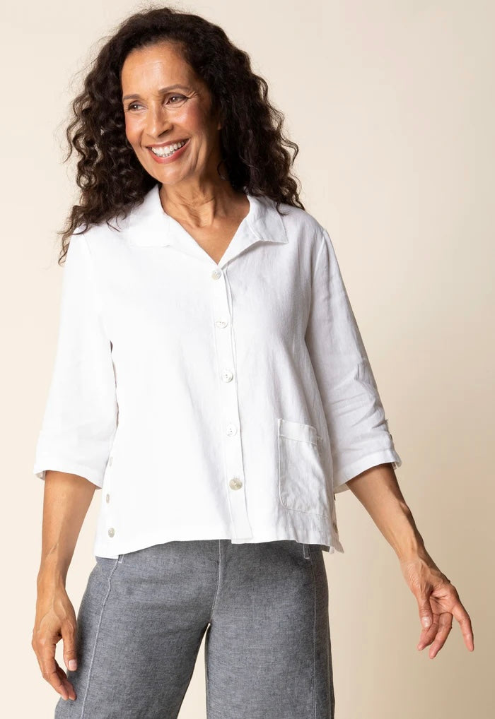 Front view (studio) — "Habitat Women's Favorite Camp Shirt in white linen, front view on smiling curly-haired model, V-neck collar, button front, patch pocket, and 3/4 sleeves, styled with grey linen trousers"
Back view — "Habitat Women's Favorite Camp Shirt in white linen, back view showing center pleat detail and relaxed fit, styled with grey linen trousers"
Side close-up — "Habitat Women's Favorite Camp Shirt in white linen, close-up side view highlighting button placket, side snap buttons, and hem detai