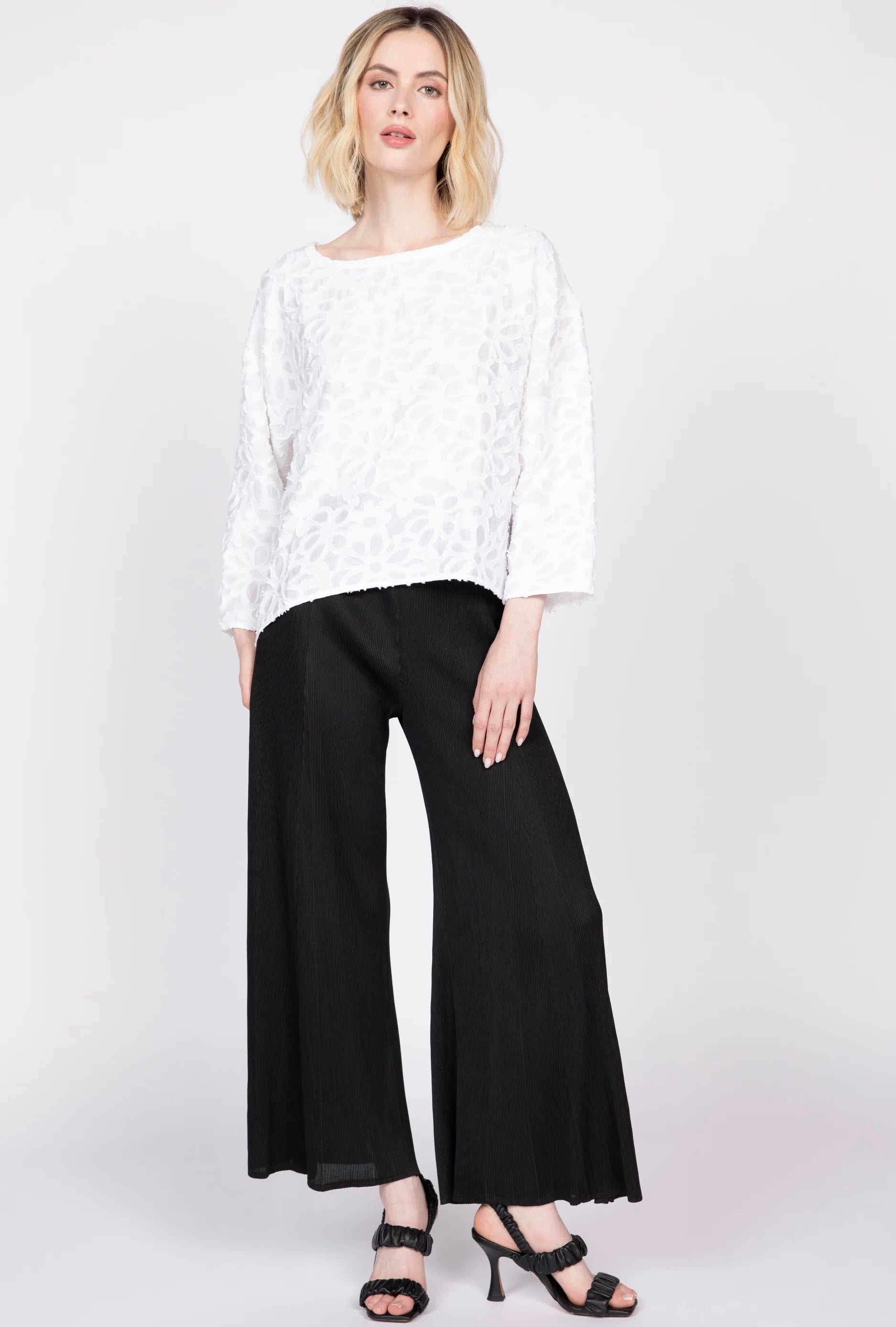 White floral appliqué topper with 3/4 sleeves, full-length front view, paired with black wide-leg trousers and heeled sandals