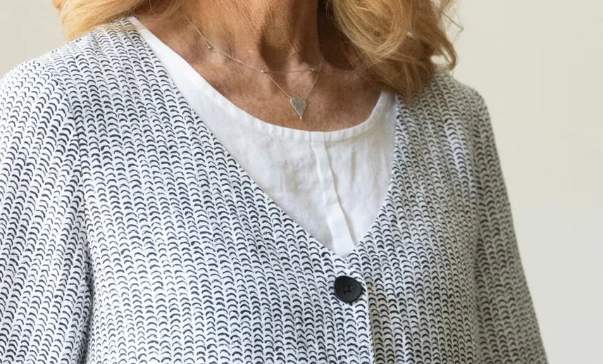 Detail of Olivia Women's Flax Stripe Button Jacket neckline and top button, layered over white linen top
