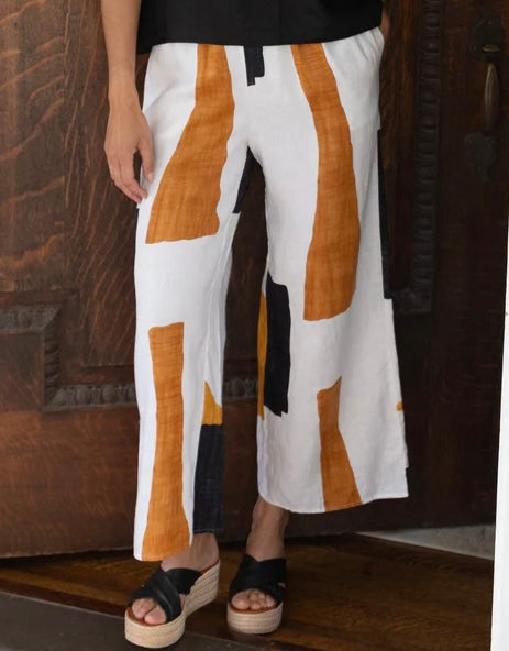 "Olivia Coastal Colorblock Breeze Pant in white with amber and black abstract print, cropped front view with black wedge sandals"