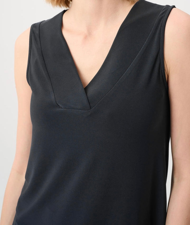 Close-up of a sleeveless black top with a deep V-neckline, shown on a model against a light gray background.
