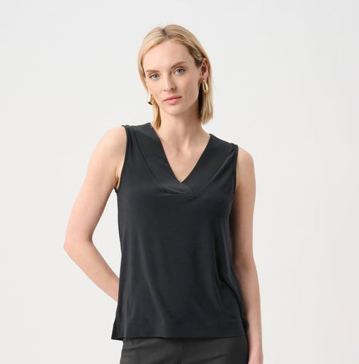 A blonde model wearing a black sleeveless V-neck top, photographed against a clean light gray studio background.